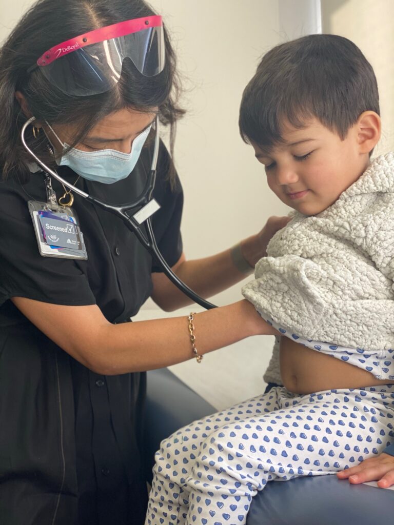 Nurse checking a young child's heartbeat with a stethescope during a checkup.