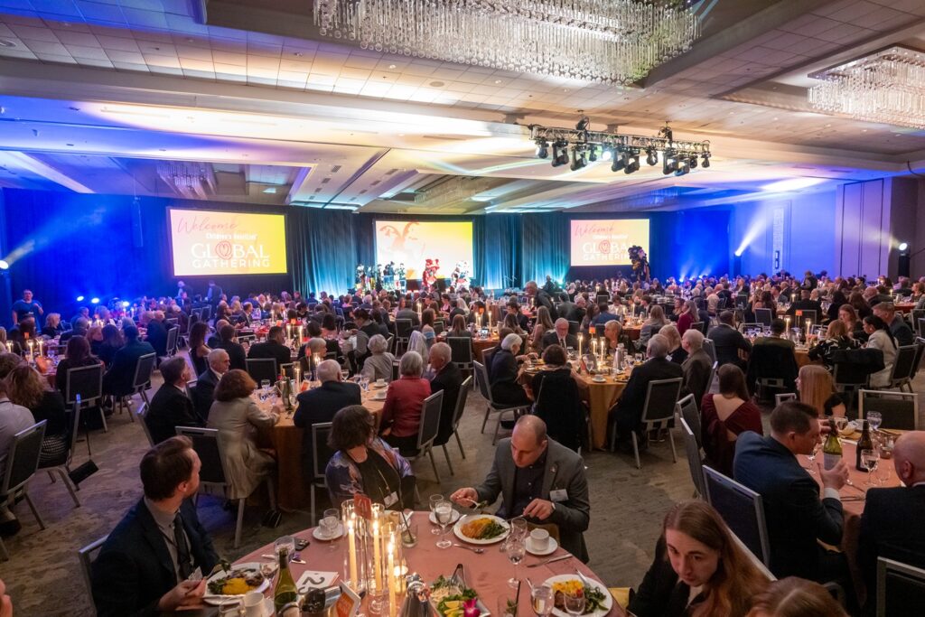 Ballroom full of people at tables with a lion performance onstage.