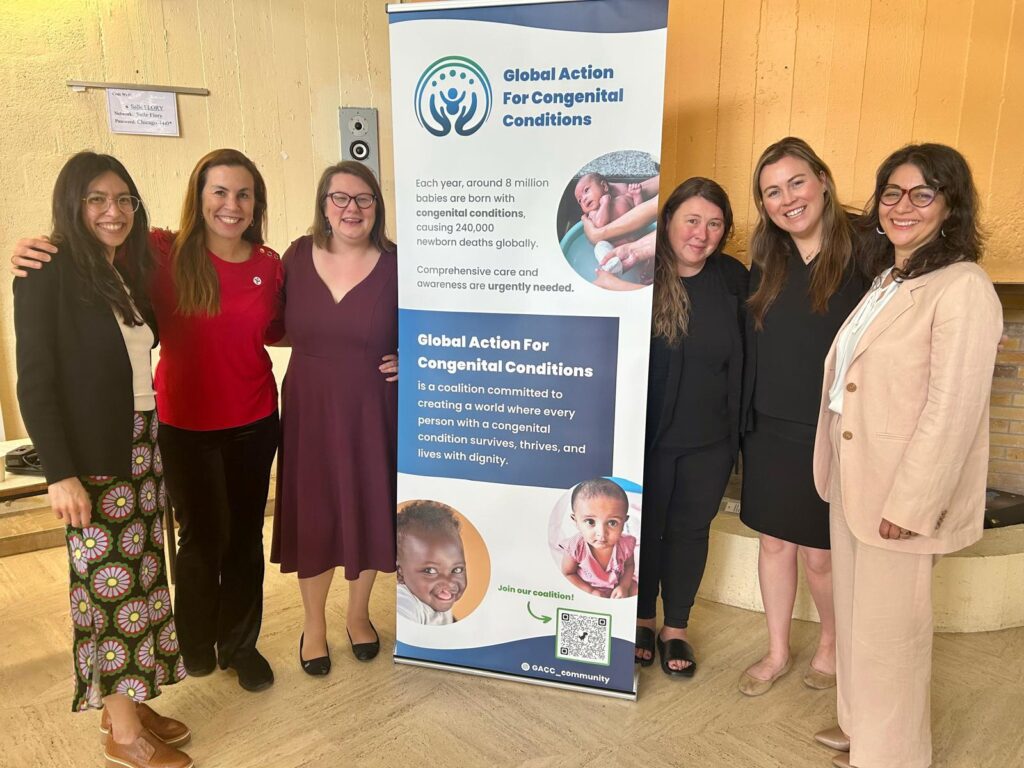Six advocates posing next to standing banner titled "Global Action for Congenital Conditions."