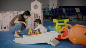 Mother watching her baby play in a hospital playpen.